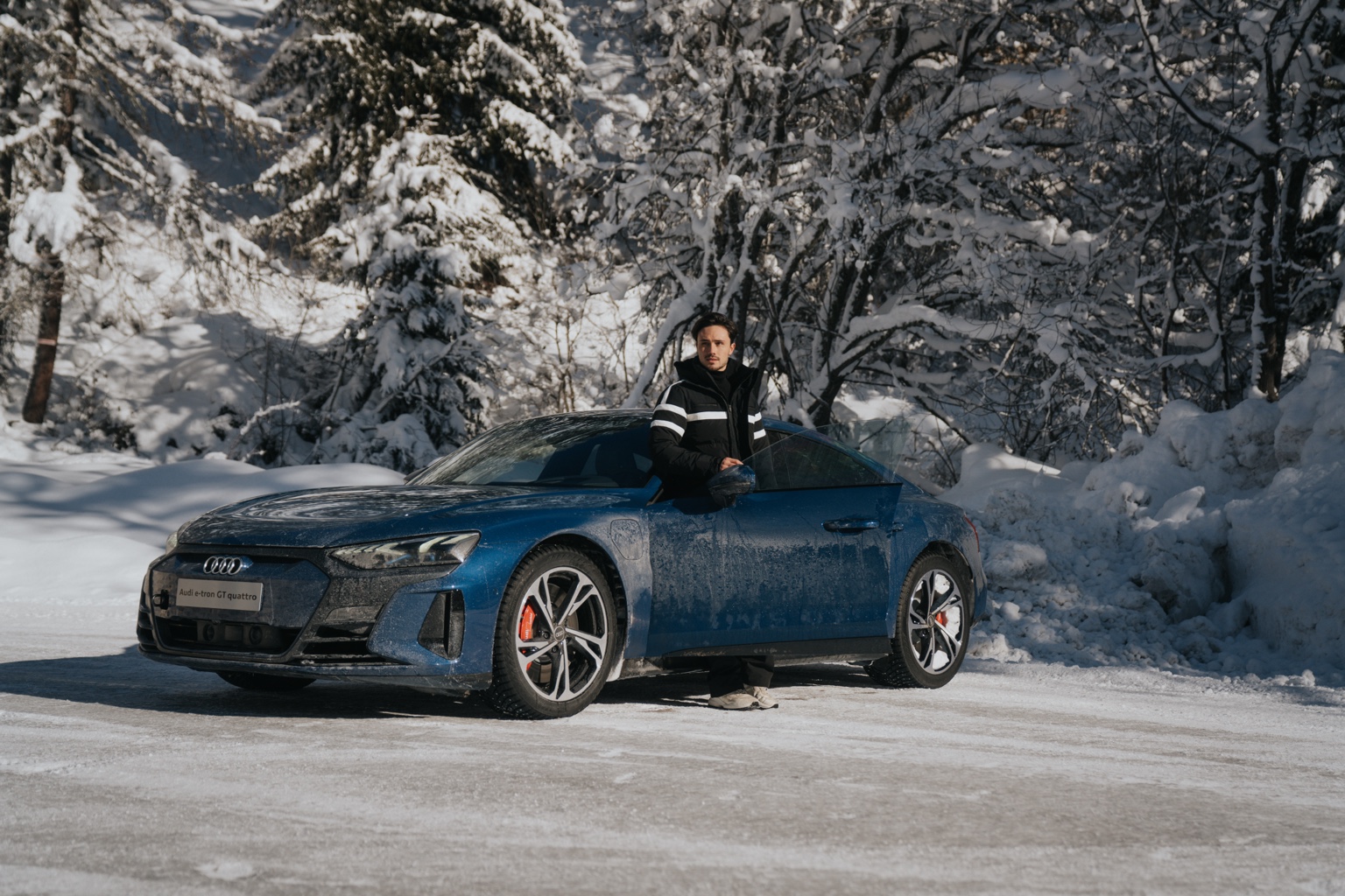 Portrait beside a blue Audi e-tron GT quattro in the snow