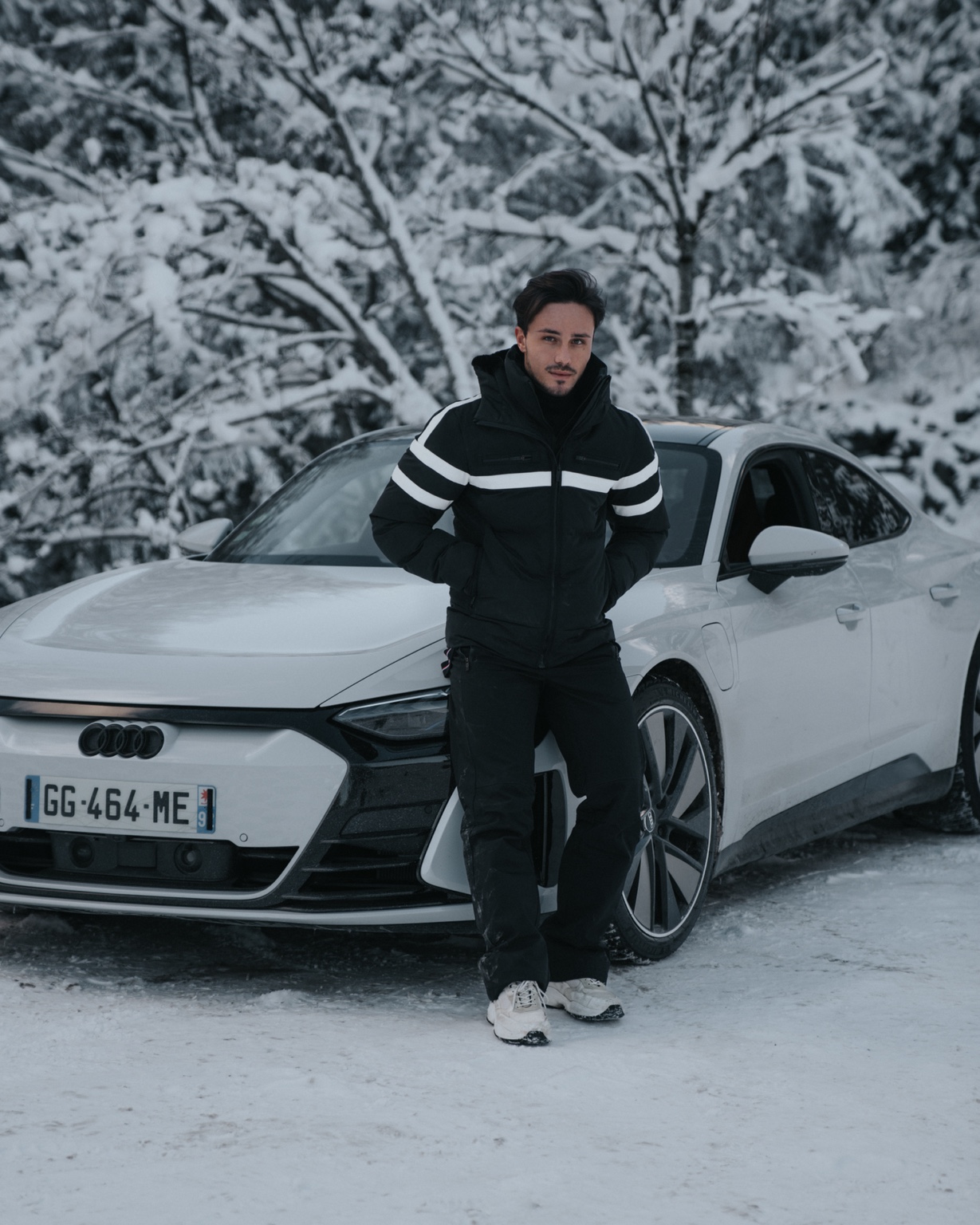 Portrait in Fusalp winter wear beside a white Audi in the snow