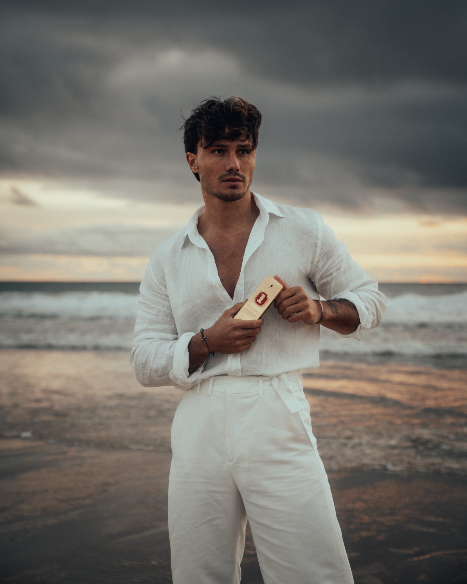 Paco Rabanne beach portrait holding the fragrance