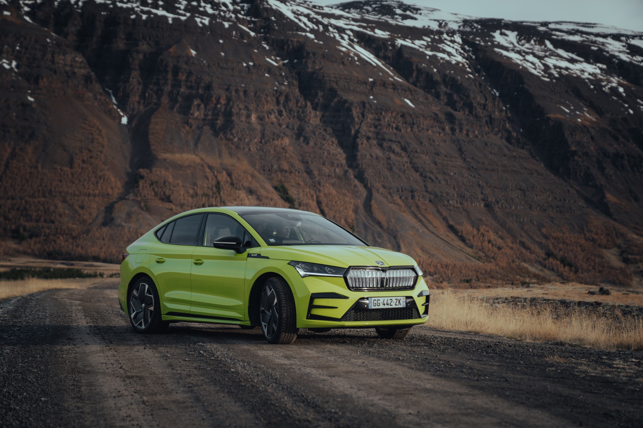 Green Skoda parked in front of a mountain backdrop