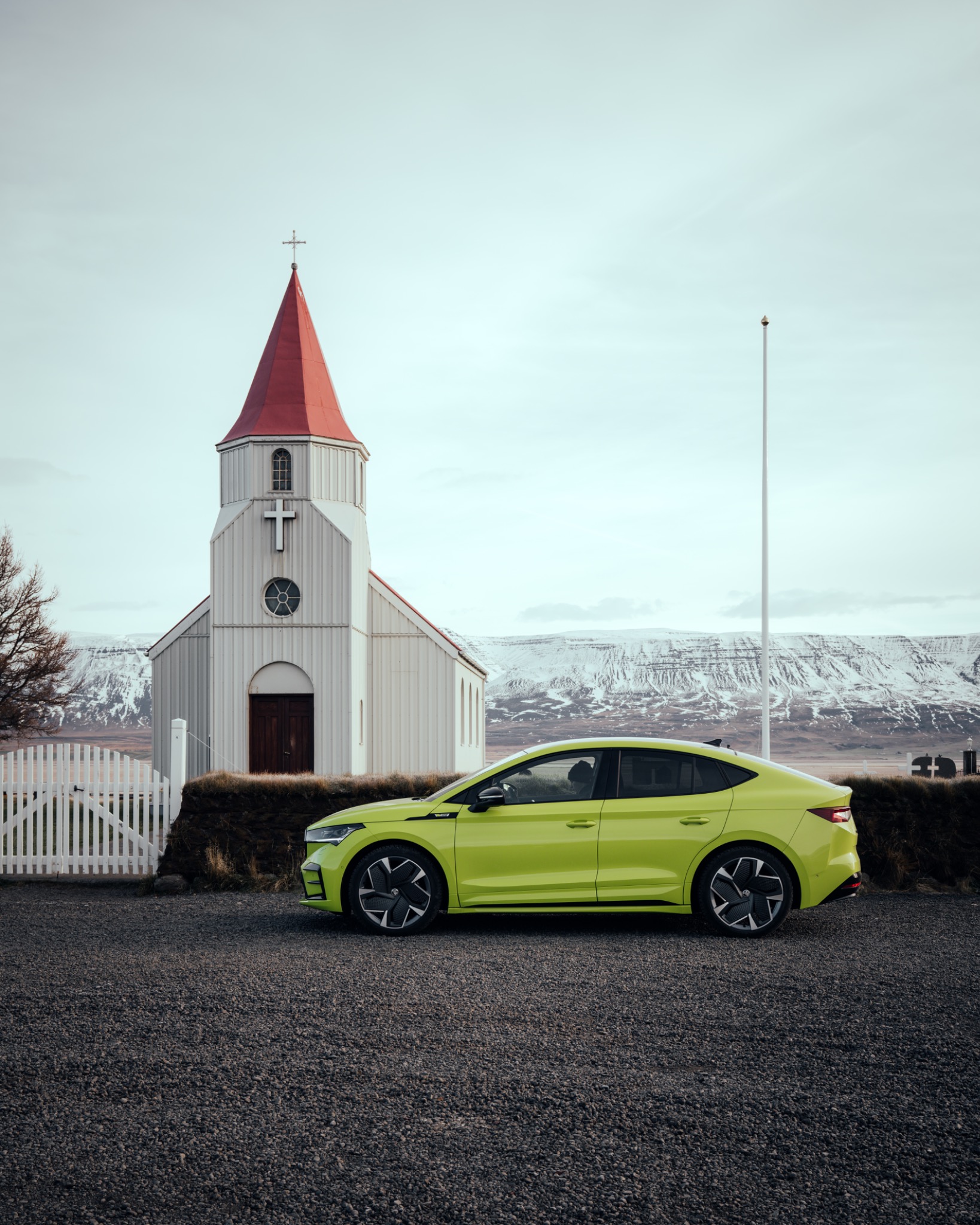 Green Skoda parked beside a church in Iceland